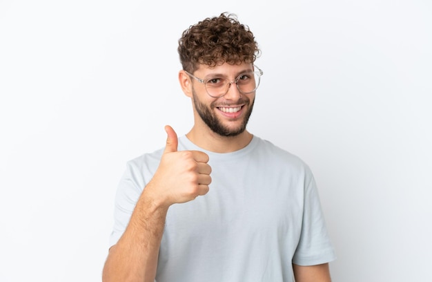 Jeune bel homme caucasien isolé sur fond blanc avec des lunettes et avec le pouce vers le haut