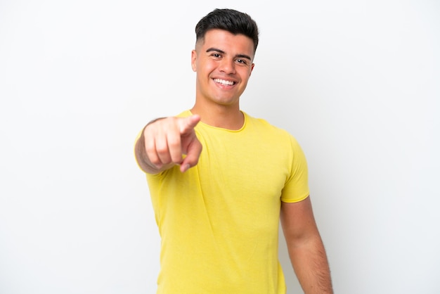 Jeune bel homme caucasien isolé sur fond blanc pointant vers l'avant avec une expression heureuse