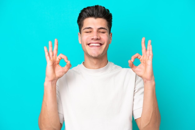 Jeune bel homme caucasien isolé sur fond bleu dans une pose zen