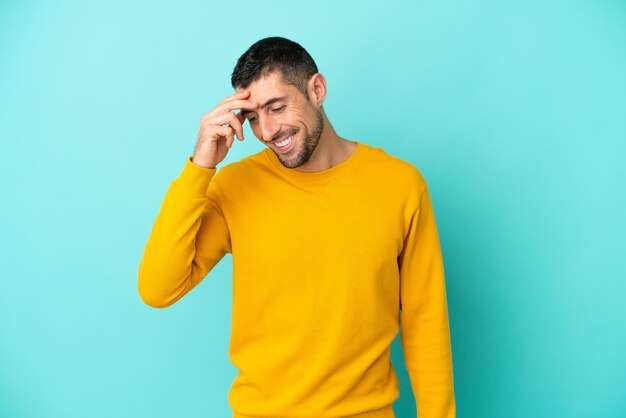 Jeune bel homme caucasien isolé sur fond bleu en riant