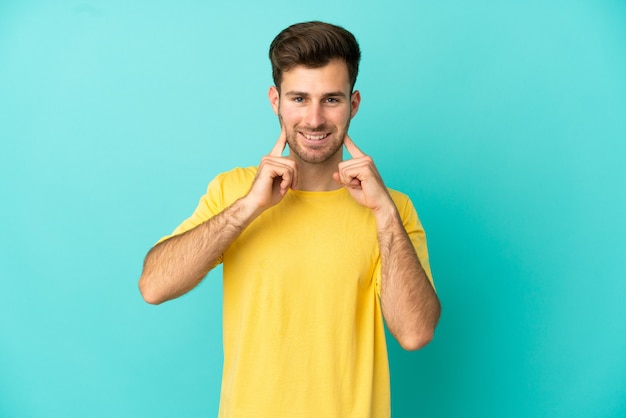 Jeune bel homme caucasien isolé sur fond bleu souriant avec une expression heureuse et agréable