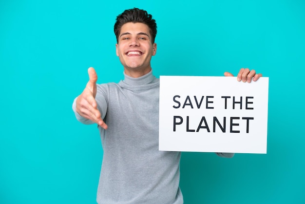 Jeune bel homme caucasien isolé sur fond bleu tenant une pancarte avec du texte Save the Planet faisant un accord