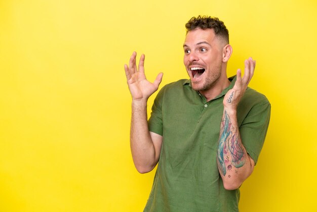 Jeune bel homme caucasien isolé sur fond jaune avec une expression faciale surprise
