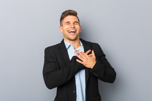 Jeune bel homme caucasien rire en gardant les mains sur le cœur, le concept du bonheur.