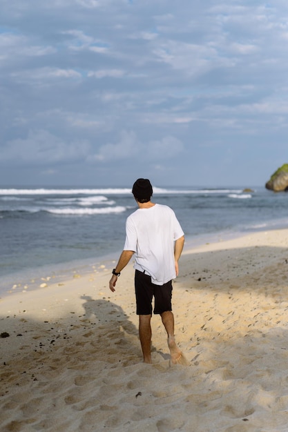 Jeune bel homme avec un charmant sourire en lunettes de soleil sur la plage.