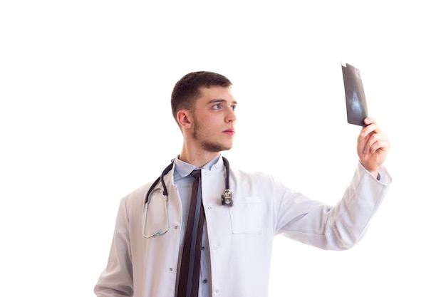 Jeune bel homme en chemise bleue cravate et robe de médecin avec stéthoscope sur son cou tenant Xray