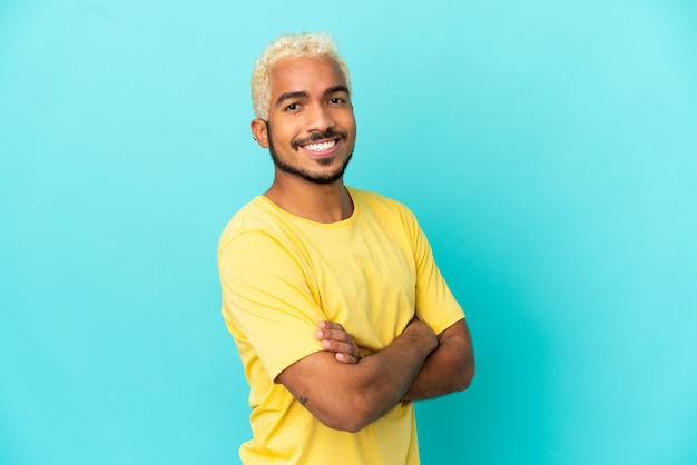 Jeune bel homme colombien isolé sur fond bleu avec les bras croisés et impatient