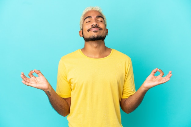 Jeune bel homme colombien isolé sur fond bleu dans une pose zen