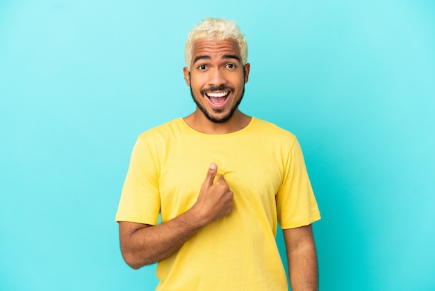 Jeune bel homme colombien isolé sur fond bleu avec une expression faciale surprise