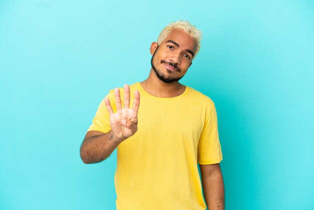 Jeune bel homme colombien isolé sur fond bleu heureux et comptant quatre avec les doigts