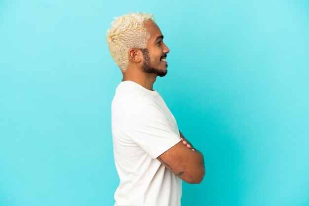 Jeune bel homme colombien isolé sur fond bleu en position latérale