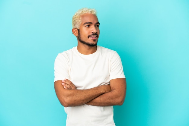 Jeune bel homme colombien isolé sur fond bleu regardant sur le côté