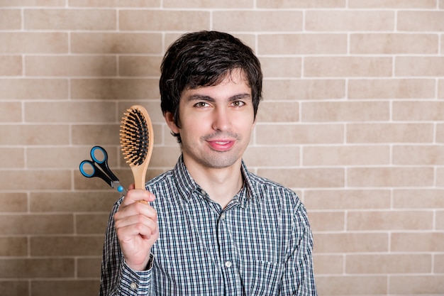 Jeune bel homme coupe ses propres cheveux à la maison.