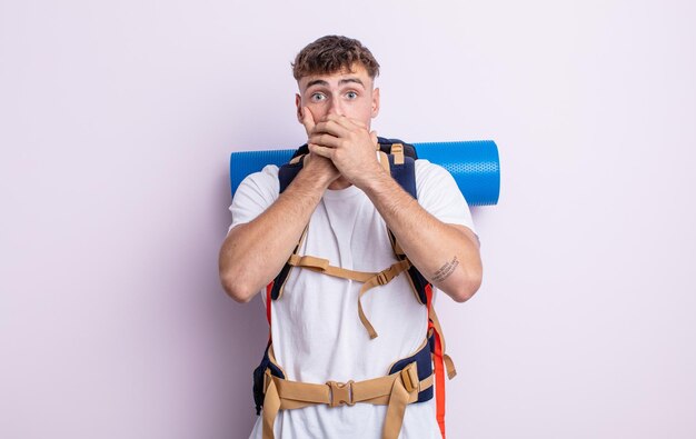 Jeune bel homme couvrant la bouche avec les mains avec un choc. notion de randonneur