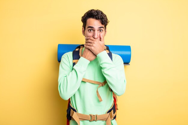 Jeune bel homme couvrant la bouche avec les mains avec un choqué