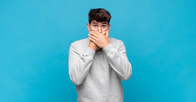 Jeune bel homme couvrant la bouche avec les mains