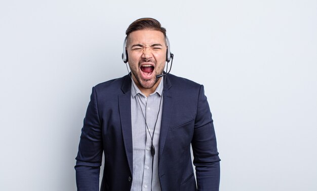 Jeune bel homme criant agressivement, l'air très en colère. concept de télémarketing