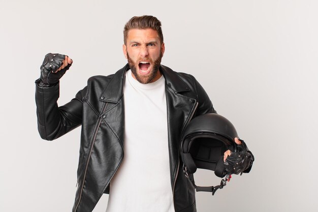 Jeune bel homme criant agressivement avec une expression de colère. concept de casque de moto