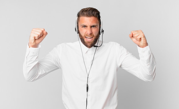 Jeune bel homme criant agressivement avec une expression de colère. concept de télémarketing