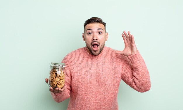 Jeune bel homme criant avec les mains en l'air. concept de bouteille de biscuits