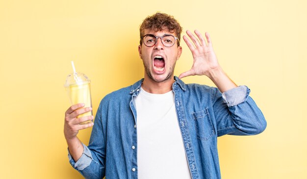 Jeune bel homme criant avec les mains en l'air. concept de milk-shake