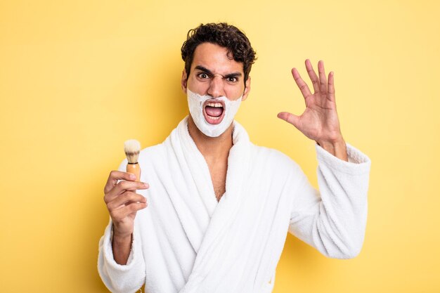 Jeune bel homme criant avec les mains en l'air. concept de rasage et de mousse