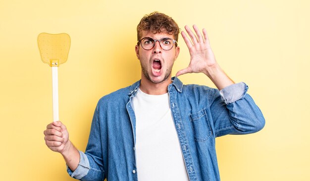 Jeune bel homme criant avec les mains en l'air. concept de tapette à mouches