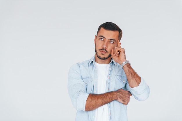 Jeune bel homme debout à l'intérieur sur fond blanc