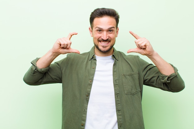 Photo jeune bel homme encadrant ou décrivant son propre sourire à deux mains, à la recherche de concept de bien-être positif et heureux,