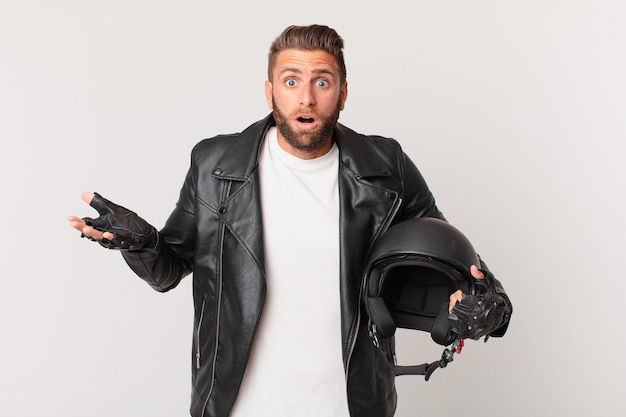 Jeune bel homme étonné, choqué et étonné d'une incroyable surprise. concept de casque de moto