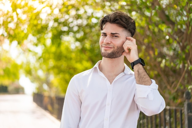 Jeune bel homme à l'extérieur ayant des doutes