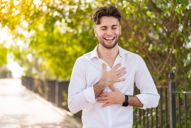 Jeune bel homme à l'extérieur souriant beaucoup