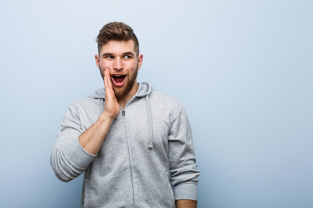 Jeune bel homme de fitness dit un secret secret des nouvelles de freinage et regarde de côté