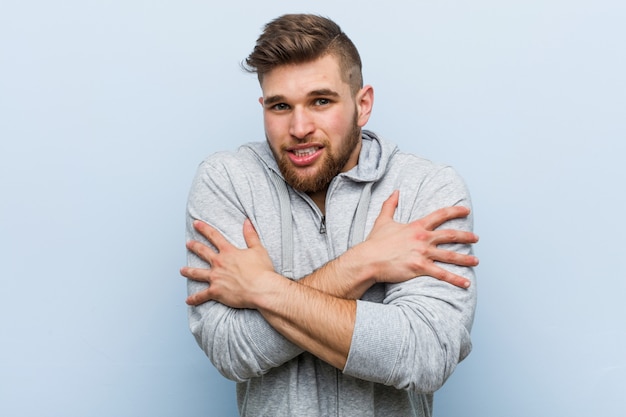 Jeune bel homme de fitness qui devient froid en raison d'une basse température ou d'une maladie.