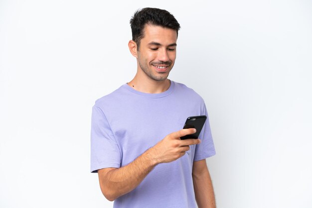 Jeune bel homme sur fond blanc isolé envoyant un message ou un e-mail avec le mobile