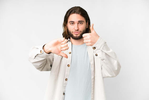 Jeune bel homme sur fond blanc isolé faisant bon signe indécis entre oui ou non