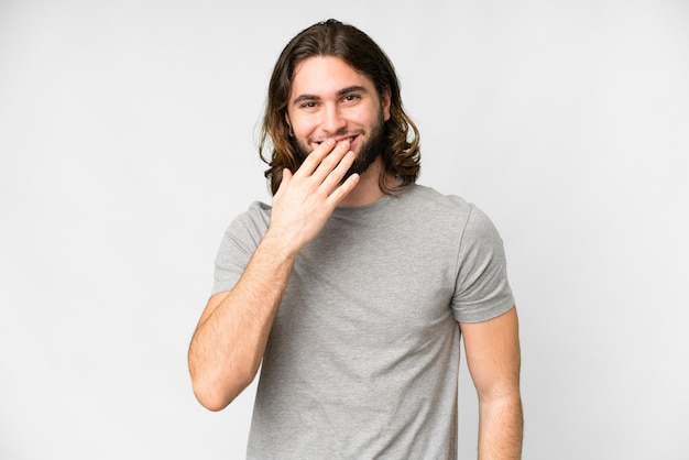 Jeune bel homme sur fond blanc isolé heureux et souriant couvrant la bouche avec la main