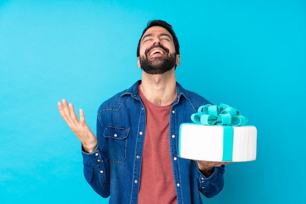 Jeune bel homme avec un gros gâteau souriant beaucoup