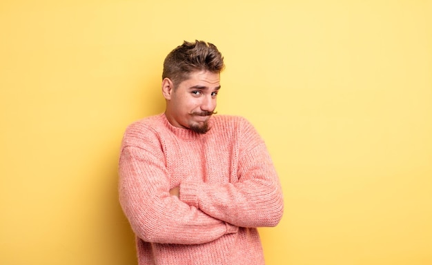 Jeune bel homme haussant les épaules, se sentant confus et incertain, doutant avec les bras croisés et le regard perplexe. étrange concept de moustache