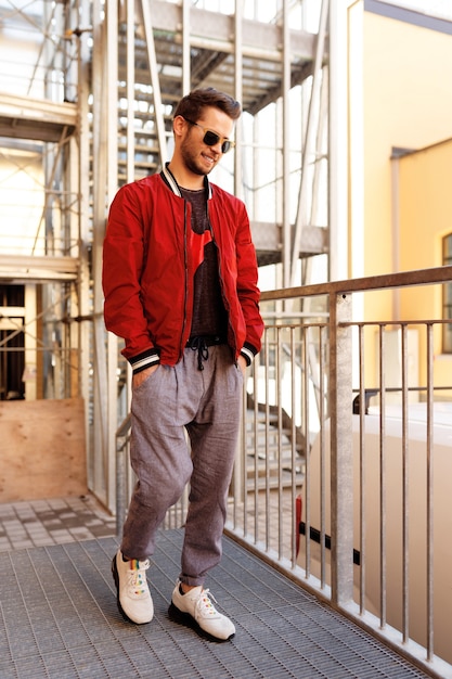 Jeune bel homme hipster en lunettes de soleil marchant dans la rue, portrait en plein air.