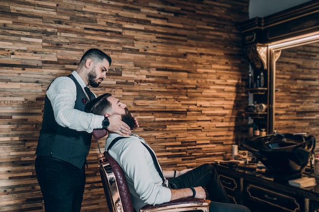 Jeune bel homme hipster visitant un salon de coiffure. Style et coupe de barbe tendance et stylée.