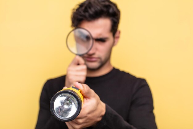 Jeune bel homme hispanique avec une loupe et une lanterne