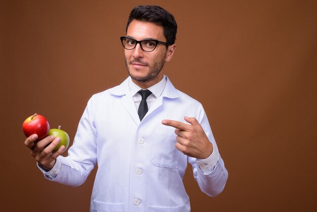 Jeune bel homme hispanique médecin sur fond marron