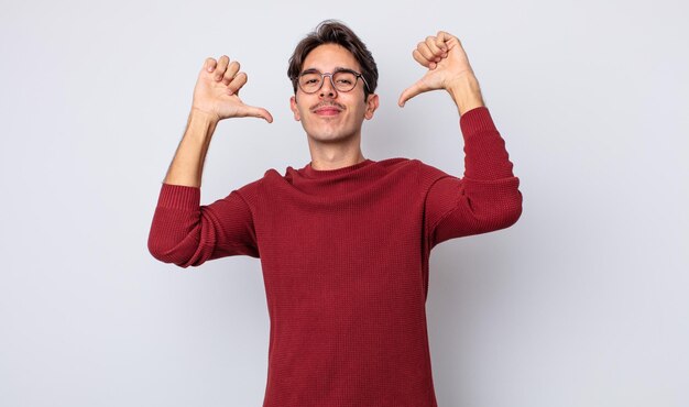 Jeune bel homme hispanique se sentant fier, arrogant et confiant, satisfait et réussi, pointant vers soi