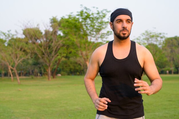 Jeune bel homme indien barbu penser et faire du jogging dans le parc