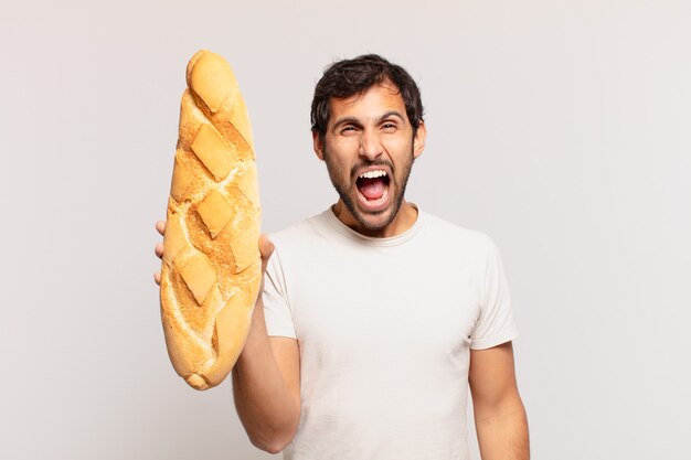 Jeune bel homme indien expression en colère et tenant un pain