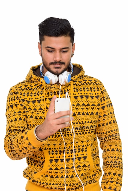 Jeune bel homme indien utilisant un téléphone mobile avec des écouteurs