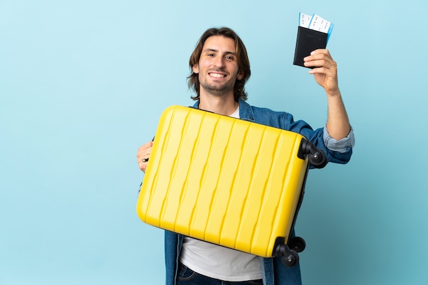 Jeune Bel Homme Isolé Sur Bleu En Vacances Avec Valise Et Passeport