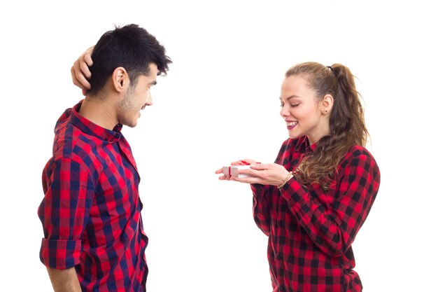 Jeune bel homme avec une jeune femme portant une chemise à carreaux rouge avec un cadeau blanc avec un ruban rouge