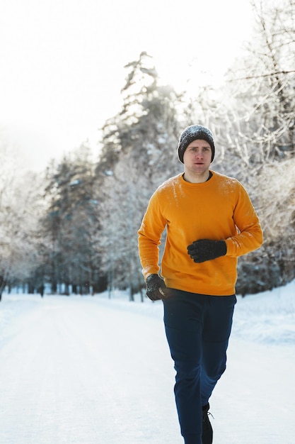 Jeune et bel homme jogger pendant son entraînement dans le parc d'hiver